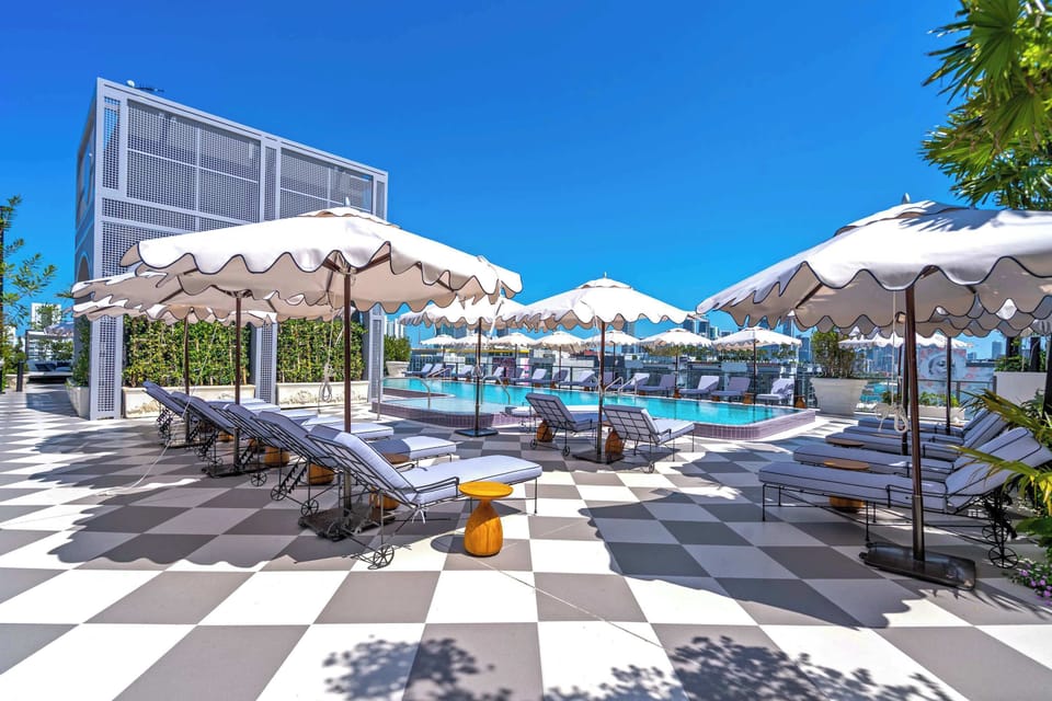 Lounge poolside in style! Chic loungers, scalloped umbrellas, and checkered tile create the ultimate rooftop oasis. The perfect spot to soak up the Miami sun.