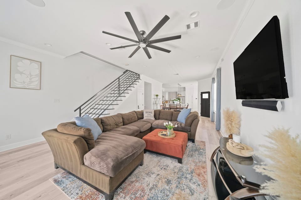 Bright open living room with large sectional, TV, and modern design
