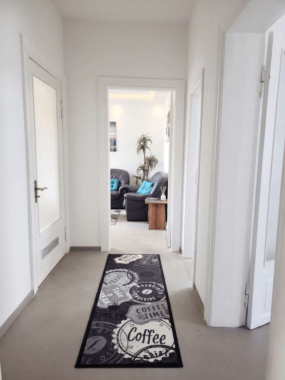 Flur – Heller, geräumiger Flur mit Kaffee-Läufer, Blick ins Wohnzimmer mit Ledersofa.
