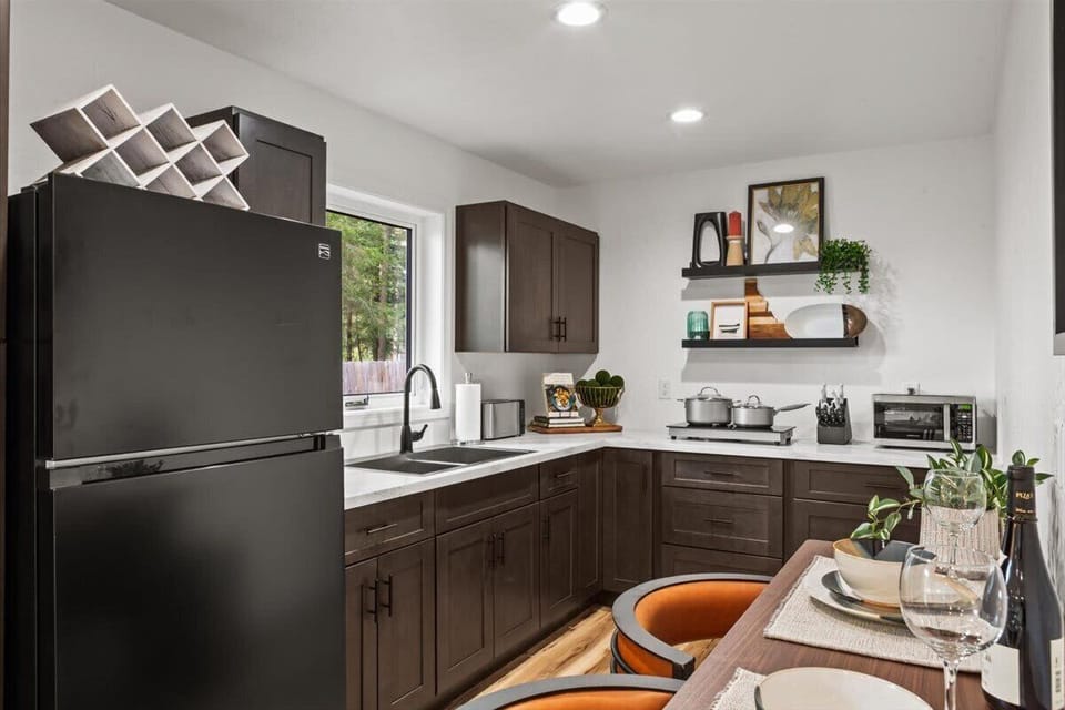 Kitchen with dark shaker cabinets, quartz counters, black fridge, and wine rack — everything you need for a proper cabin dinner in