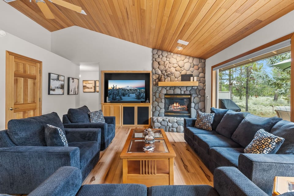 Sink into plush sofas by the crackling stone fireplace as warm wood beams frame your mountain getaway perfect for cozy evenings.