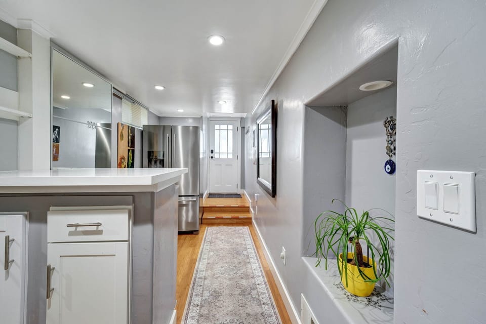 A bright hallway entrance with original artwork & a full size refrigerator