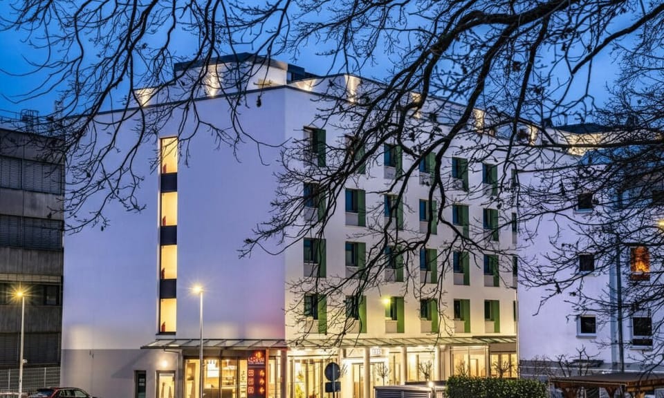Arrive to a sleek, modern hotel glowing at dusk.