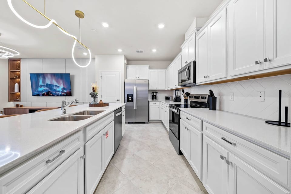 Discover a bright kitchen with modern white cabinetry and spacious quartz countertops, ideal for your culinary adventures. The open layout connects effortlessly to the living area, creating a warm space for cooking and.