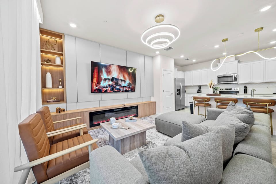 Welcome to a cozy living area with soft gray couches for relaxation, warm wood accents, and stylish lighting. Enjoy the sleek entertainment setup and a fireplace, creating a delightful atmosphere for your evenings.