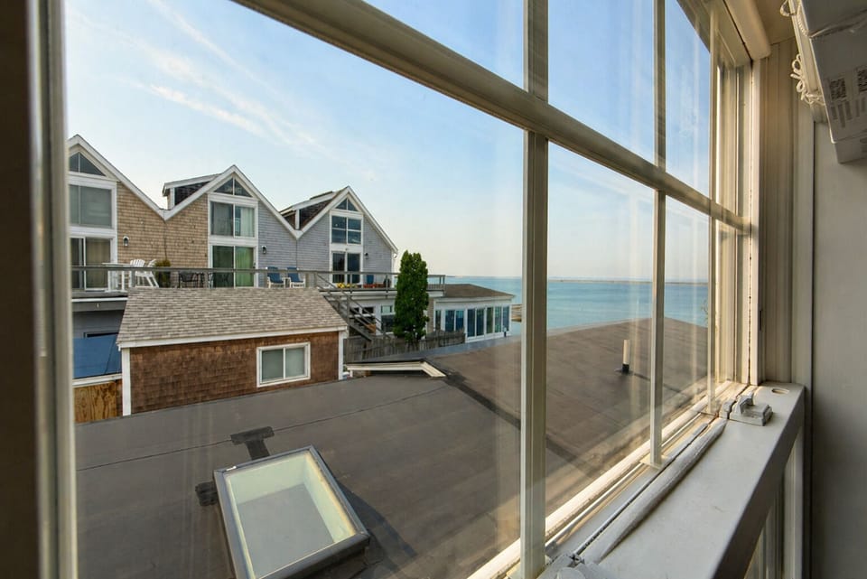 Bright window view overlooking coastal homes and peaceful water beyond
