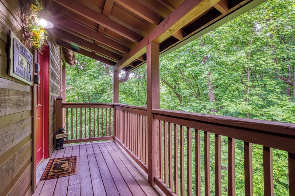 Charming covered porch with red door and peaceful wooded views