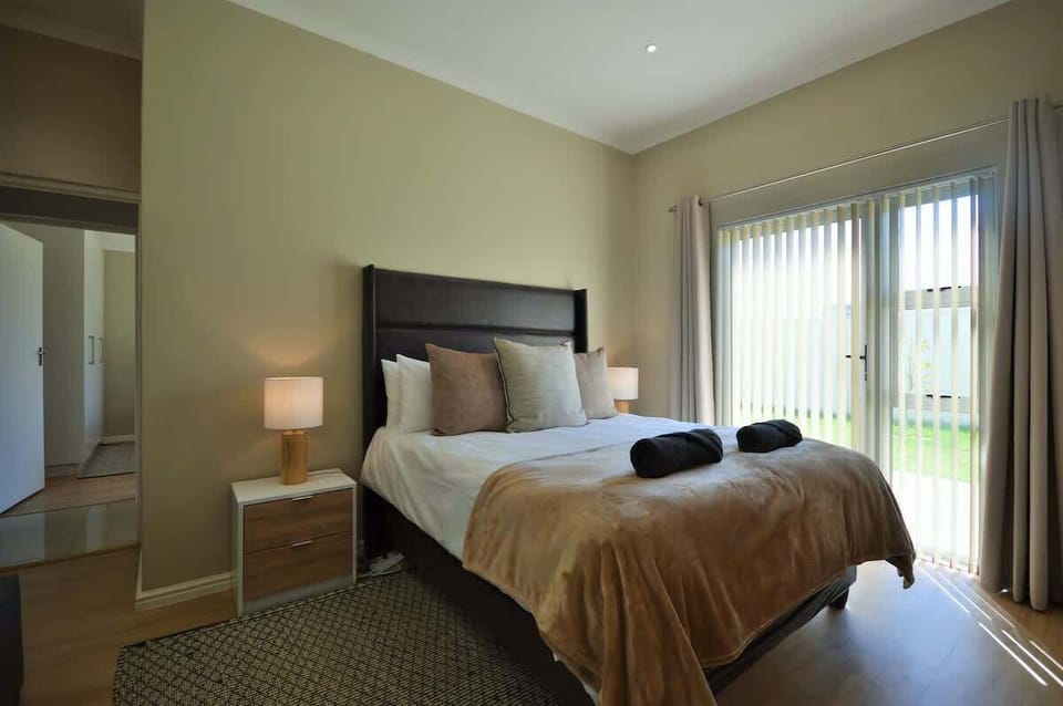 Sunlit bedroom with upholstered platform bed, twin bedside lamps and sliding door to garden - warm and quietly restful