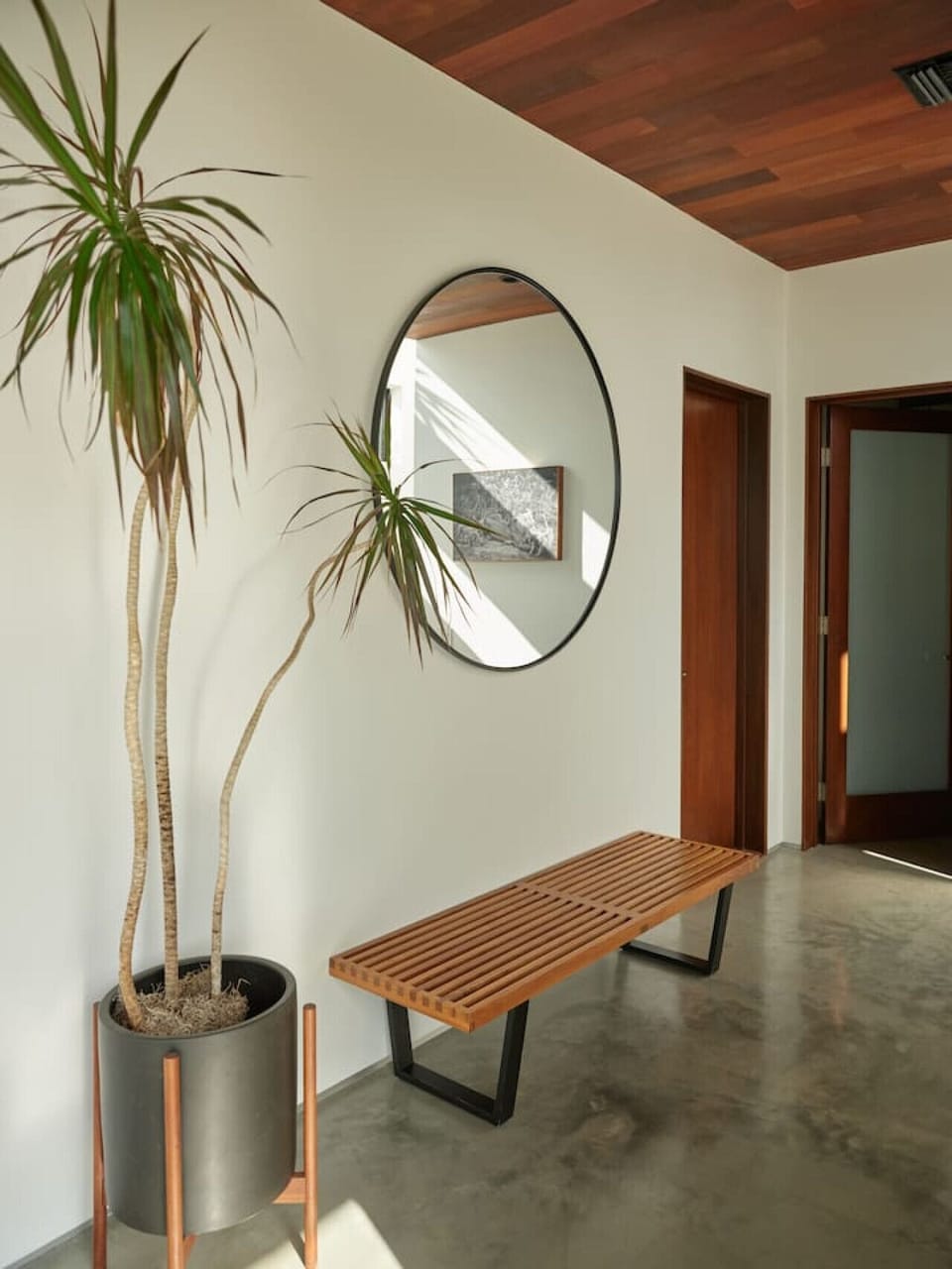 A Nelson bench, a round mirror, and a dracaena. Hallway styling done right.