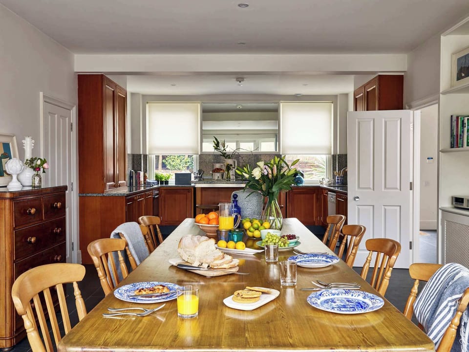 Contemporary dining area with long wooden table and open-plan design
