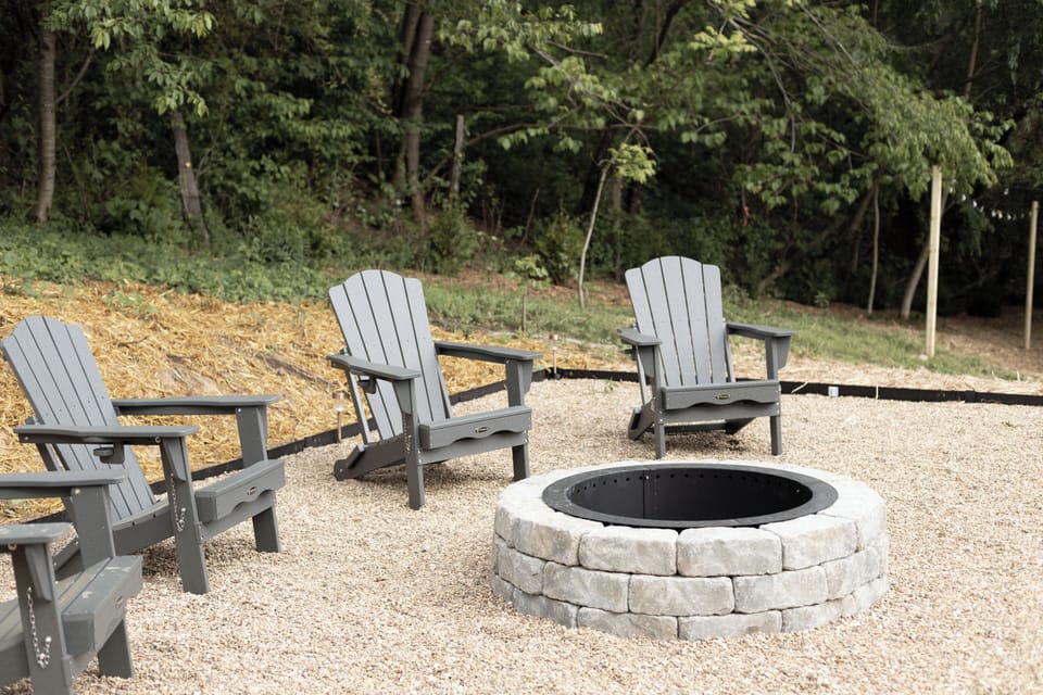 Woodland fire pit with Adirondack seating for cozy nights under the stars.