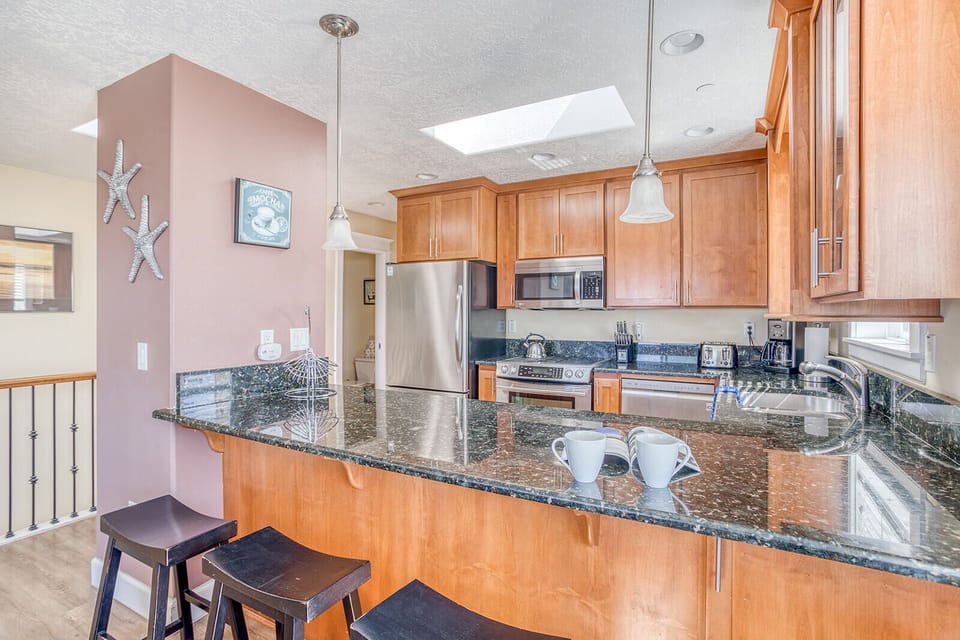 Your fully equipped kitchen features granite countertops, stainless steel appliances, and a breakfast bar perfect for morning coffee together.