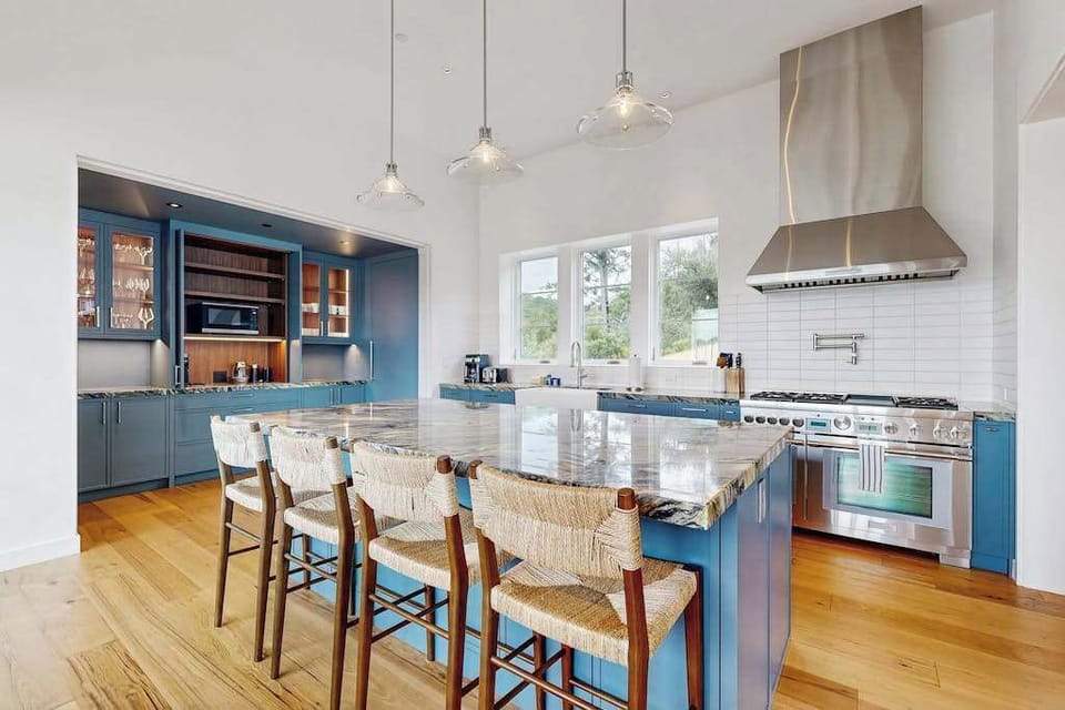 Channel your inner chef in this designer kitchen with blue cabinetry, granite island bar seating, and pro-grade stainless steel appliances ready for farm-to-table feasts.