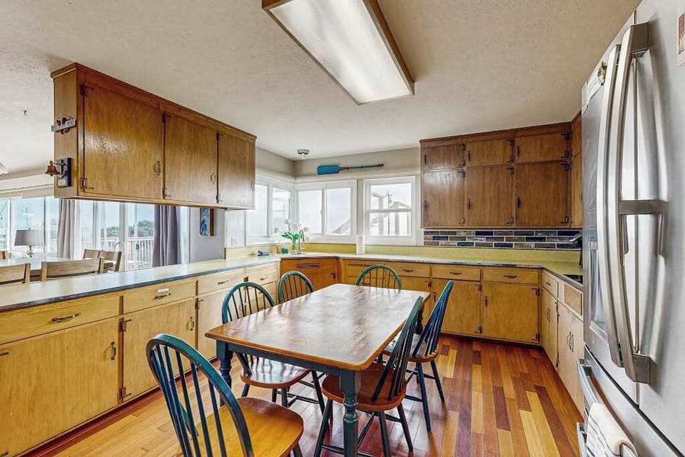 Prepare meals together in this sun-filled coastal kitchen with warm wood cabinetry and plenty of counter space for entertaining.
