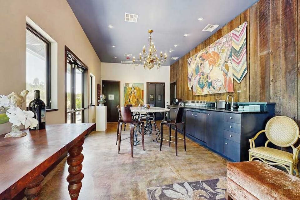 Raise a glass in the stunning barn great room—soaring ceilings, a reclaimed wood accent wall, chandelier, and kitchen bar set the stage for unforgettable gatherings.