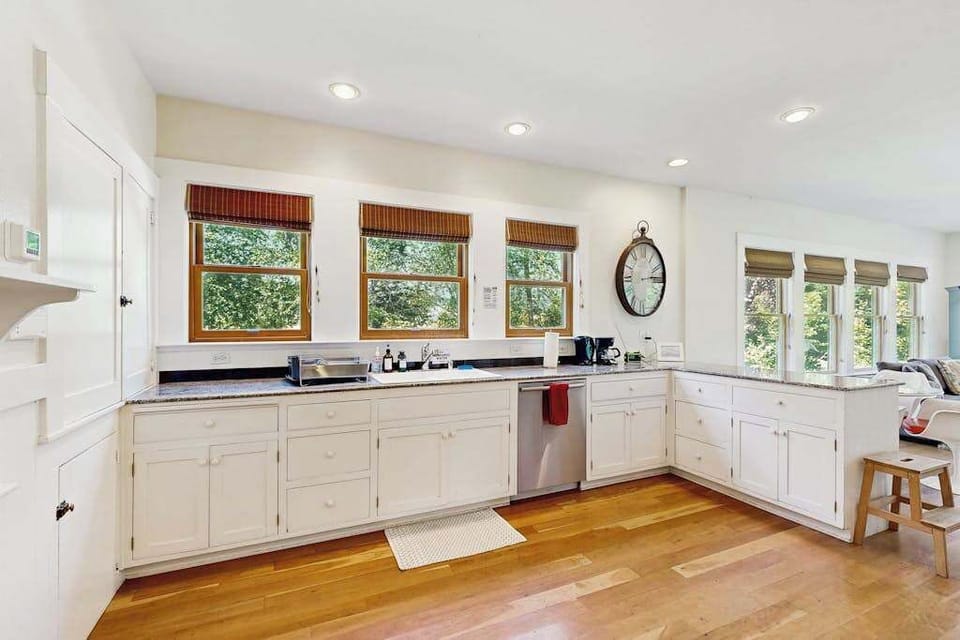 Cook like a local in your sun-drenched farmhouse kitchen with white cabinetry, hardwood floors, and vineyard views through every window.