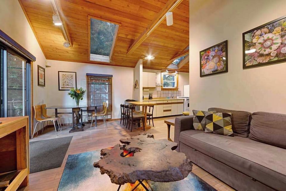 Gather in the open-plan living area where vaulted wood ceilings, eclectic art, and a live-edge coffee table set a warm wine country tone.