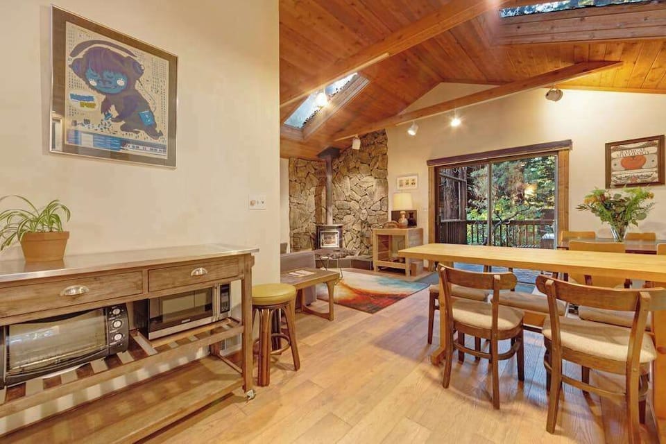 Share a wine country feast at the dining table with views of the vaulted ceiling and cozy wood-burning fireplace beyond.