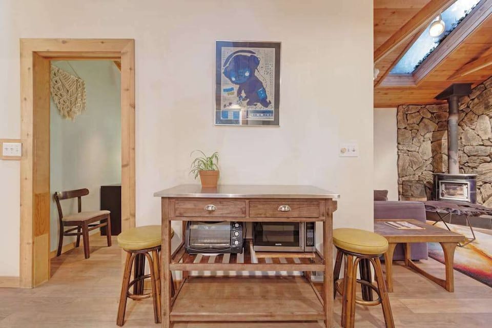 Sip local wine at the kitchen bar while the wood-burning fireplace warms the open living space beyond.