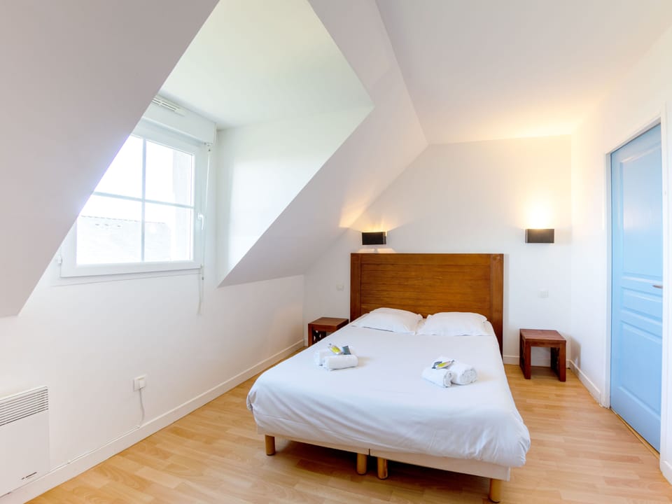 Double bed with white linens — wake up and step straight onto the private terrace overlooking the bay
