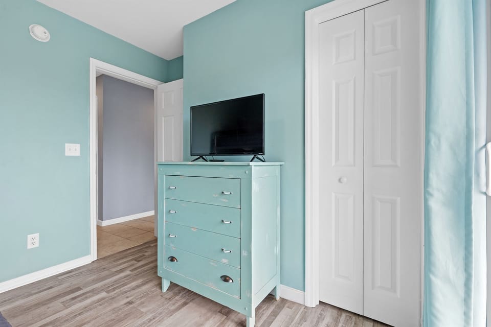 A bright coastal bedroom with storage and a TV for downtime