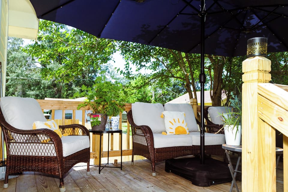 Shaded private deck with cozy seating and peaceful tree-filled views