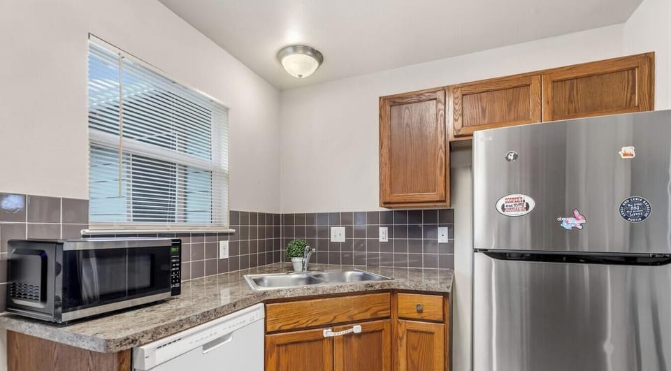 Full-size stainless fridge, dishwasher, and window light make this kitchen feel like home.