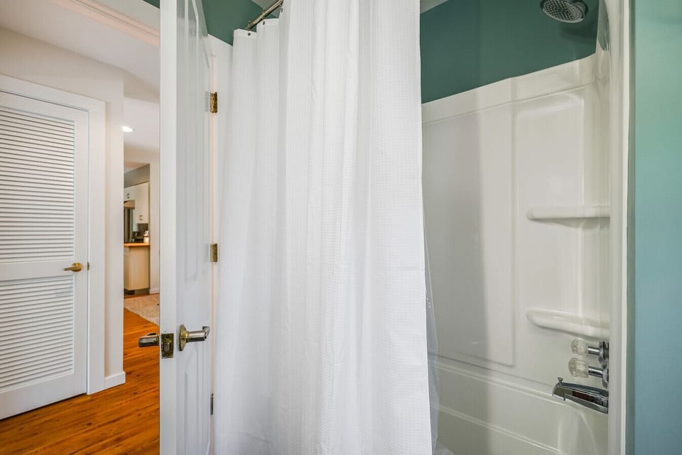 Sparkling clean shower and tub combination featuring built-in shelving for your toiletries and a crisp white waffle-knit curtain.
