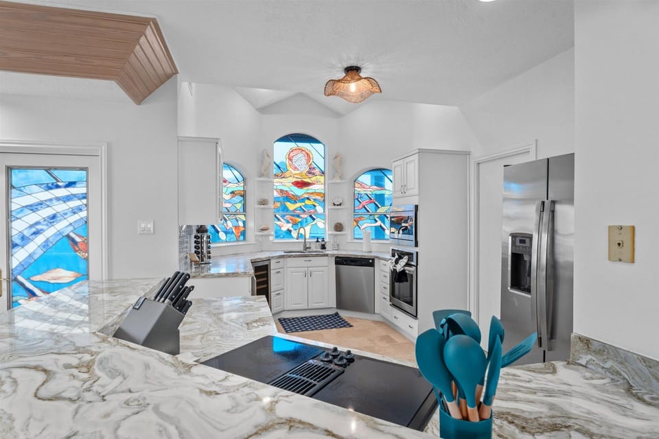Kitchen workspace with island prep area, stainless appliances, and decorative window accents, perfect for cooking and entertaining.