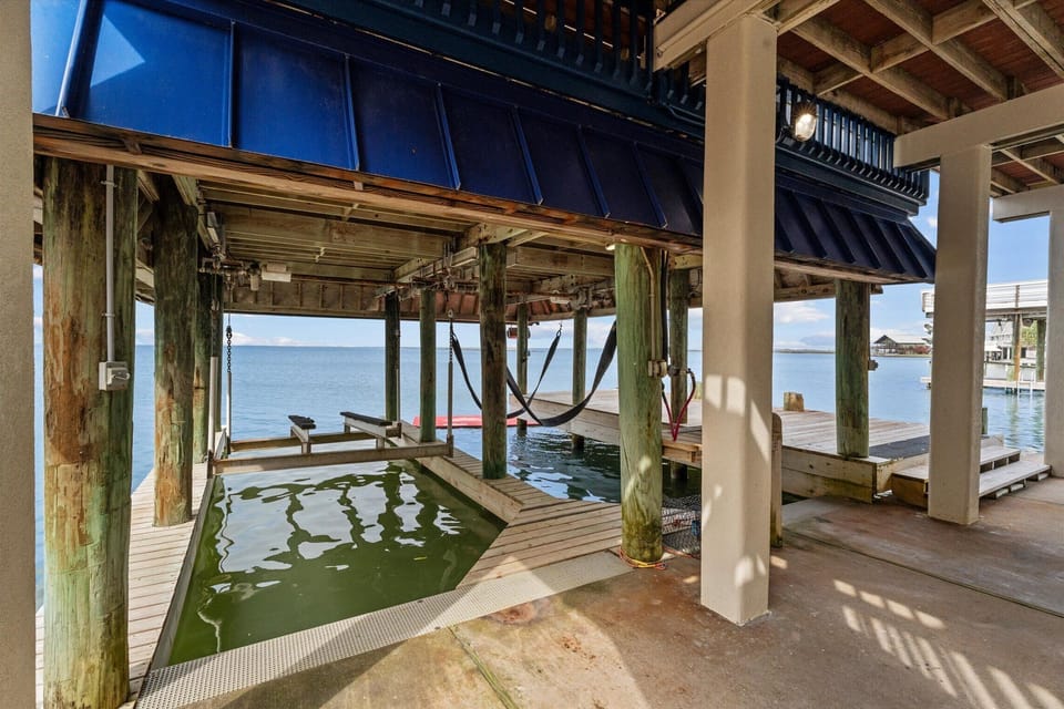 Waterfront covered space beneath the home with structural beams and open views, enhancing coastal outdoor living.