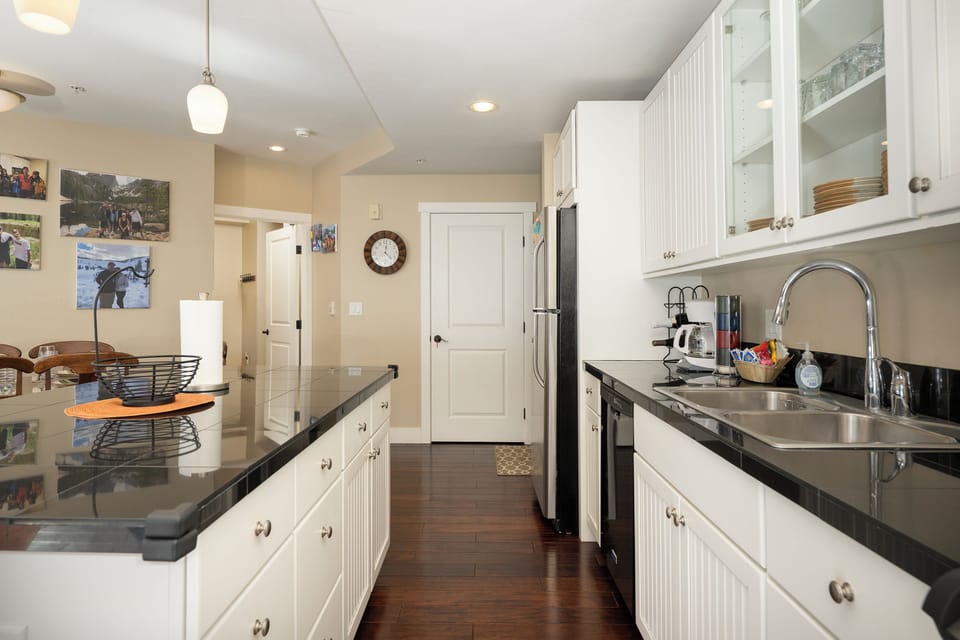 Your fully equipped galley kitchen at Base Camp 305 features sleek white cabinets, granite countertops, and stainless appliances for effortless meal prep.