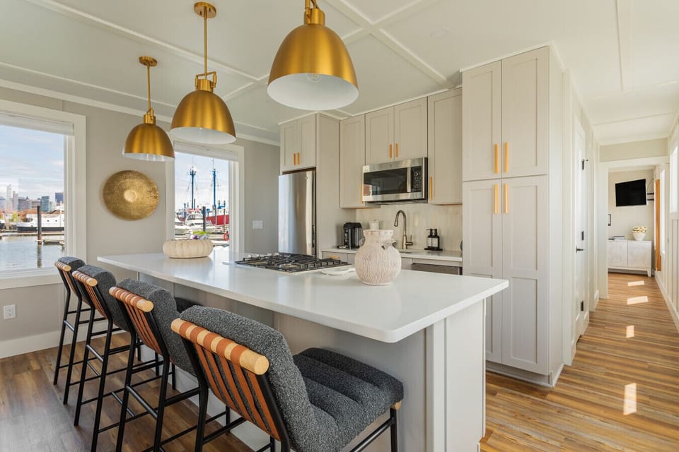 The kitchen island sits at the center of it all, with the Manhattan skyline visible through the window and a clear sightline through the entire length of the suite.