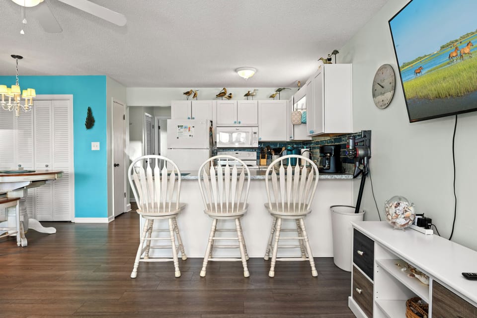 Settle into your bright, coastal-inspired space where white shaker cabinets meet turquoise accents. Gather at the breakfast bar on charming spindle stools, whip up meals in your fully-equipped kitchen, and enjoy local charm throughout.