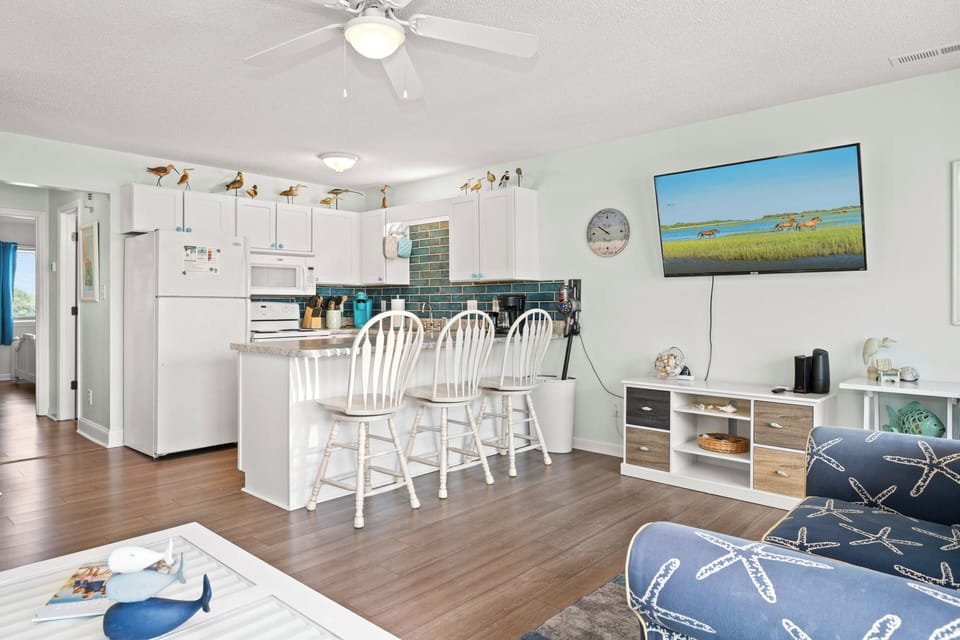 Open, airy space blends living and kitchen areas with coastal charm. Relax in the living room or gather at the breakfast bar under coastal décor. Modern appliances and soothing beach colors invite you to feel right at home.