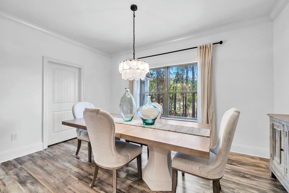 You'll love gathering around this elegant dining table, where natural light streams through large windows and stylish fixtures create the perfect ambiance for memorable meals.