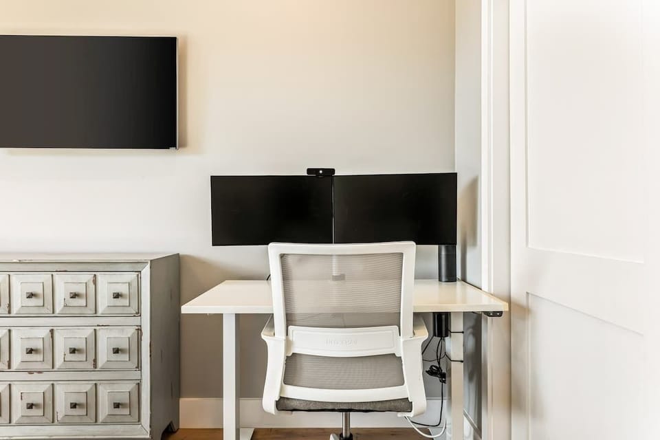 Dedicated workspace with dual monitors and desk setup, ideal for remote work during your stay.