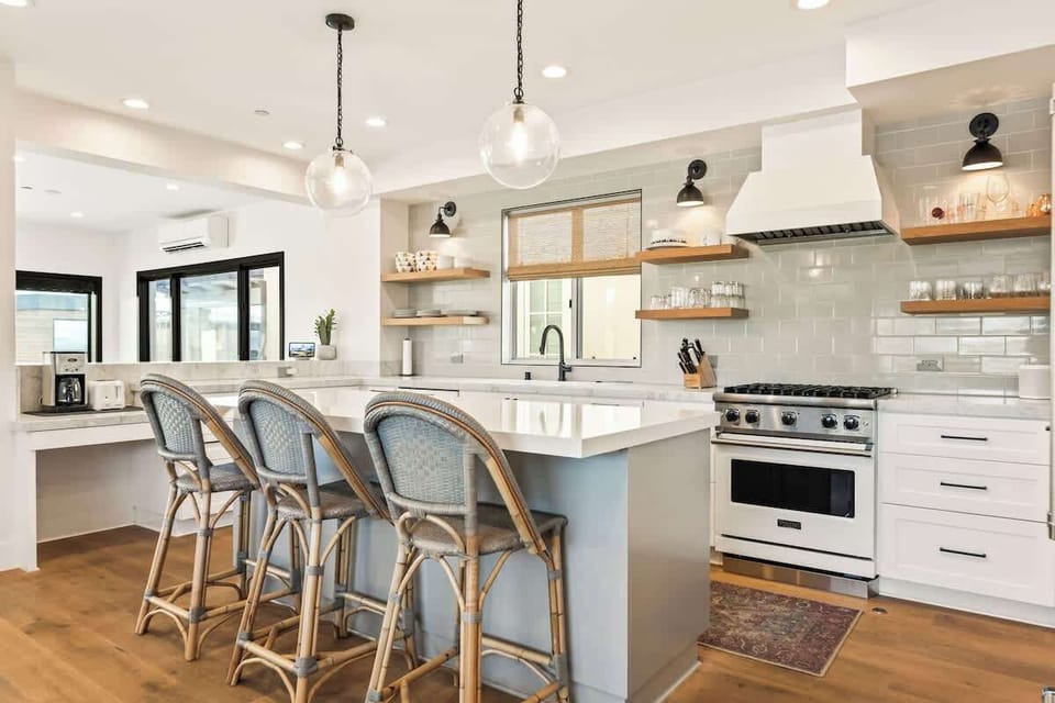 Beautifully designed kitchen featuring a large island with bar seating, gas range, and open shelving for easy cooking and entertaining.
