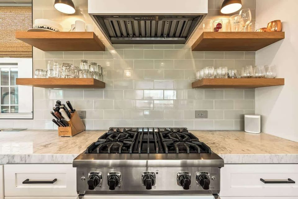 Cook with ease on the professional gas range, complemented by marble countertops and open shelving stocked with glassware and essentials.