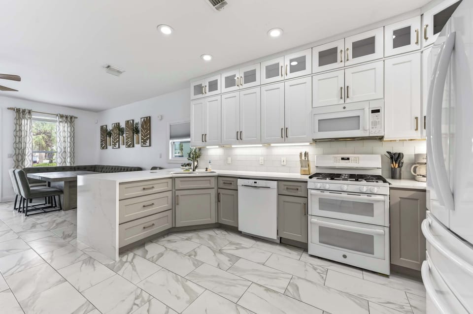 Open-Concept Two-Tone Kitchen

A wide view of the modern kitchen featuring two-tone cabinetry and an elegant waterfall quartz peninsula. The space transitions effortlessly into an adjacent dining area, tied together by chic marble-look tile floors.