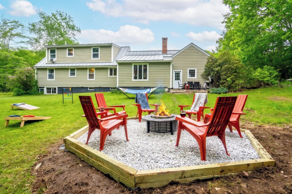 A relaxed outdoor setup with a firepit, comfortable chairs, and a hammock