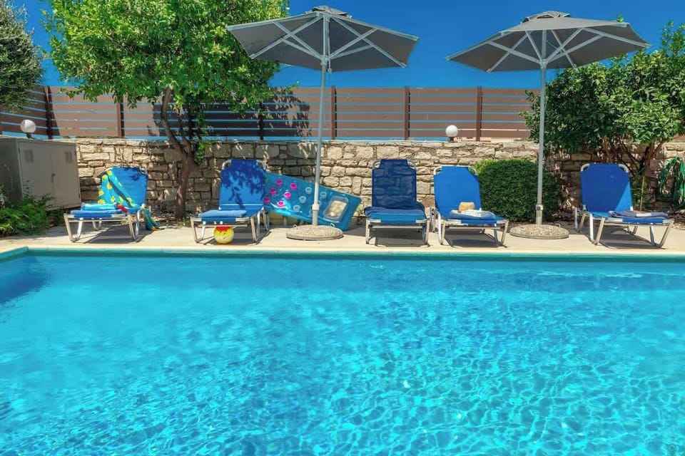 The private swimming pool sits at the heart of the outdoor space, with sun loungers arranged for long, relaxed days under the Cretan sun.