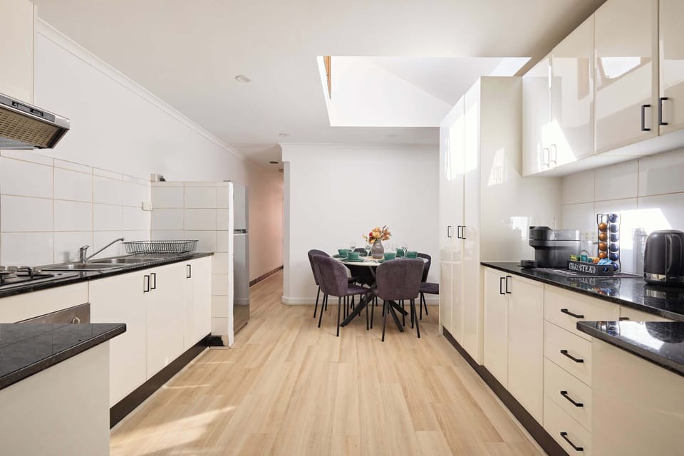 Spacious open-plan kitchen and dining area designed for modern living, featuring sleek cabinetry, generous storage, quality finishes, and abundant natural light from the overhead skylight.