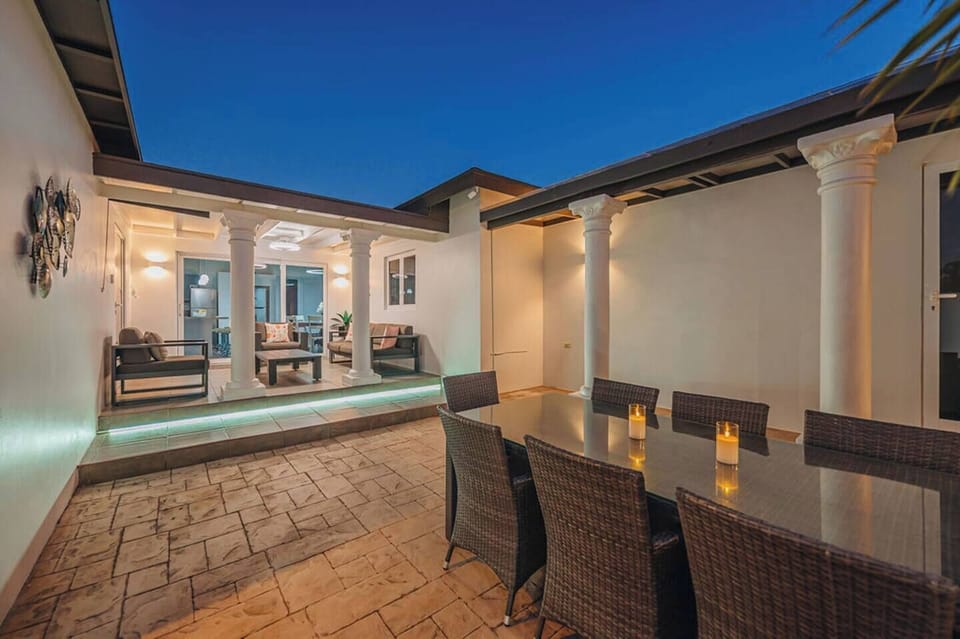 Evening patio scene with soft lighting, covered columns, and dining setup creating a warm, inviting outdoor atmosphere