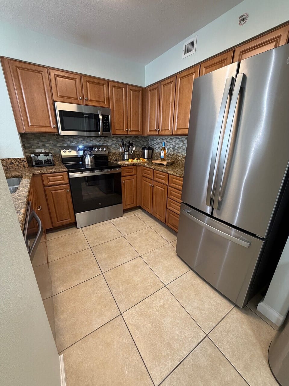 Your fully equipped kitchen awaits with stainless steel appliances, granite countertops, and rich wood cabinetry—perfect for preparing memorable meals.