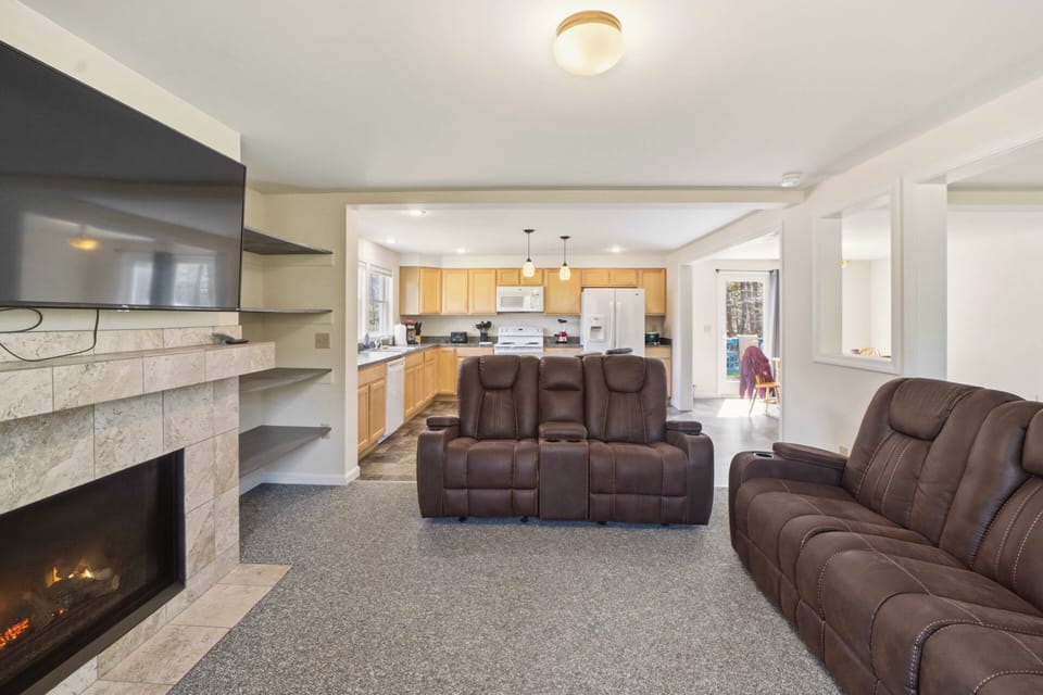 Sink into plush leather recliners while your fireplace crackles nearby. This open living area flows seamlessly into the full kitchen, perfect for relaxing.