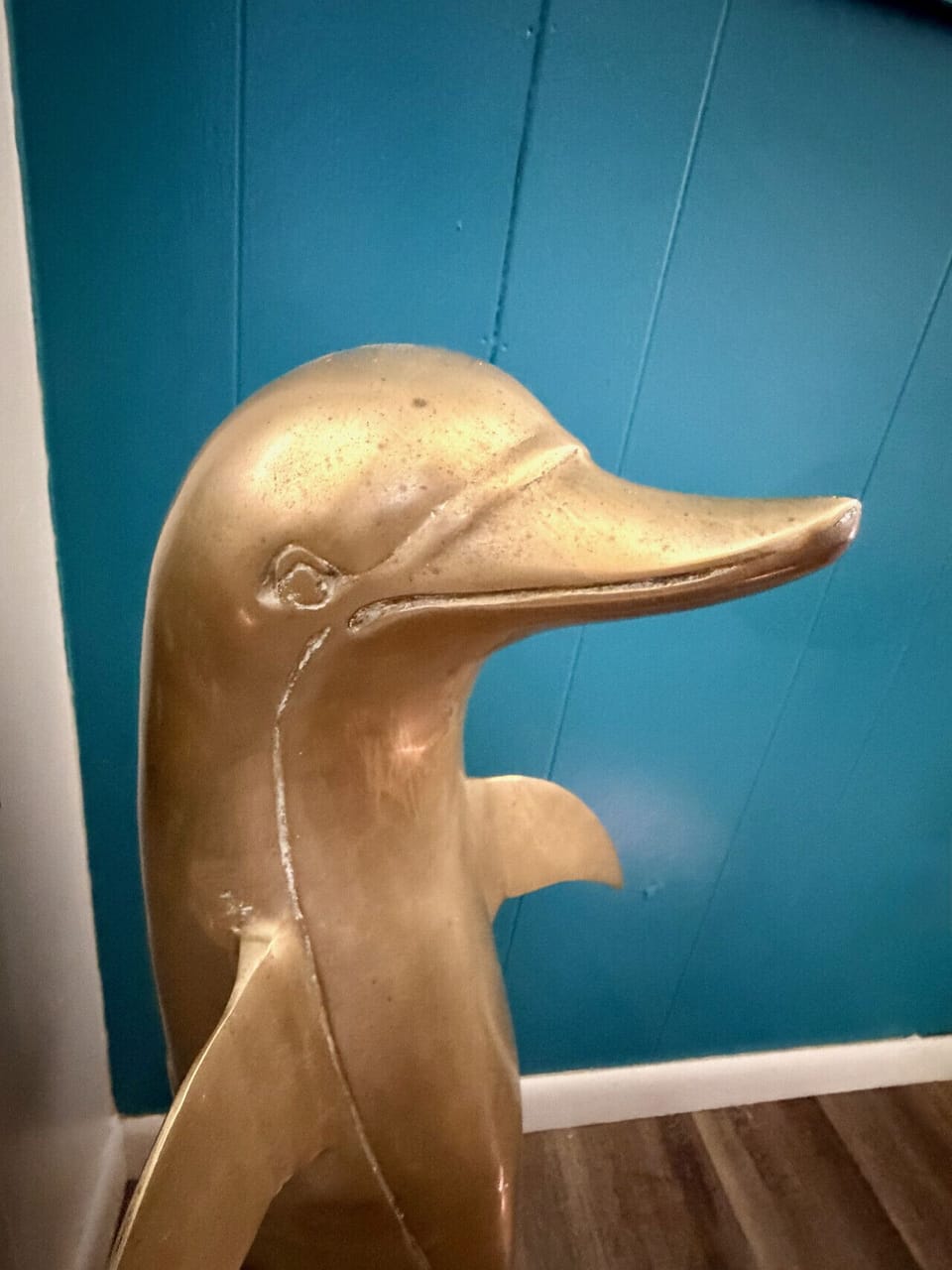 The Naturalist`s Cabin — vintage brass dolphin accent on a deep teal wall