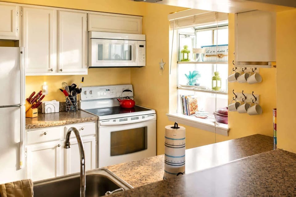 Bright and cozy kitchen with modern appliances, warm lighting, and clean white cabinetry.