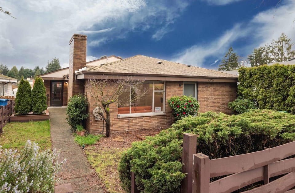 Charming brick exterior with a private entrance and welcoming greenery.