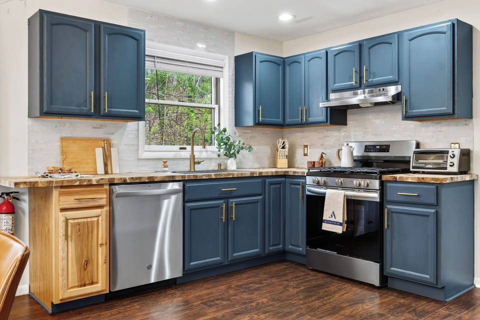 Modern blue‑and‑wood kitchen with warm finishes and everything set for easy cooking. (The Hollow)