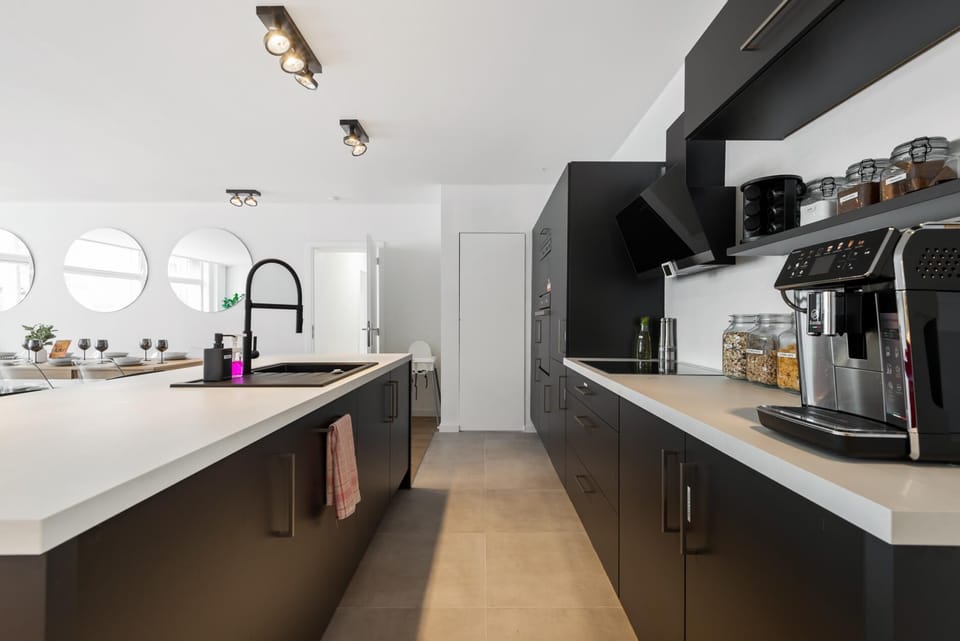 Modern kitchen with a spacious island, sleek countertops, and integrated appliances. Open shelving and ample workspace make it easy to prepare meals, while the bright layout connects seamlessly to the dining and living area.